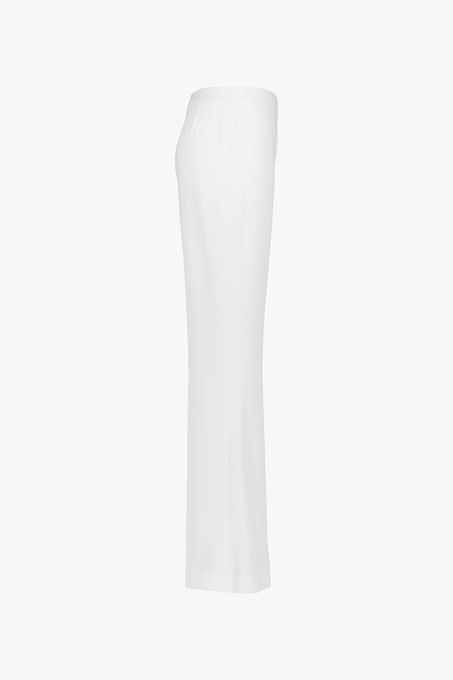 Pantalon blanc une coupe évasée et taille haute structurée. Fermeture latérale invisible. Matière fluide, légère