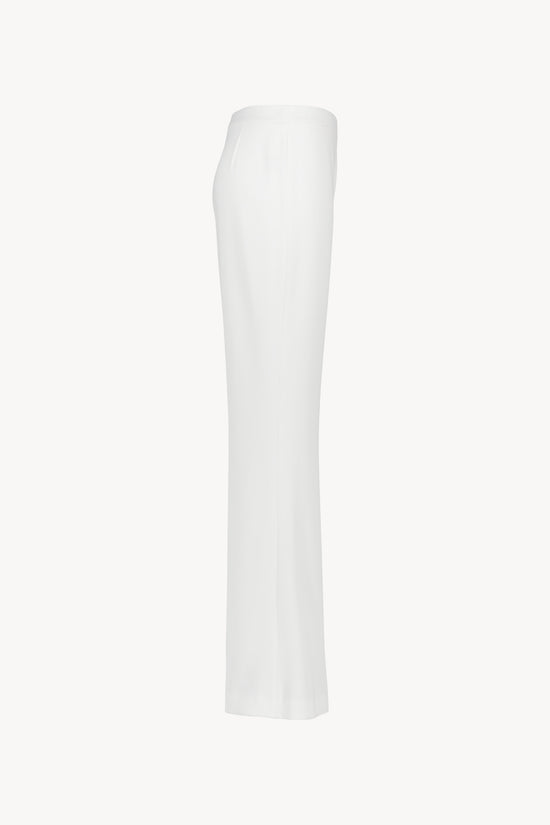 Pantalon blanc une coupe évasée et taille haute structurée. Fermeture latérale invisible. Matière fluide, légère