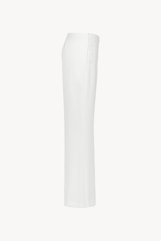 Pantalon blanc avec  coupe évasée et fermeture zippée ton sur ton sur le côté 