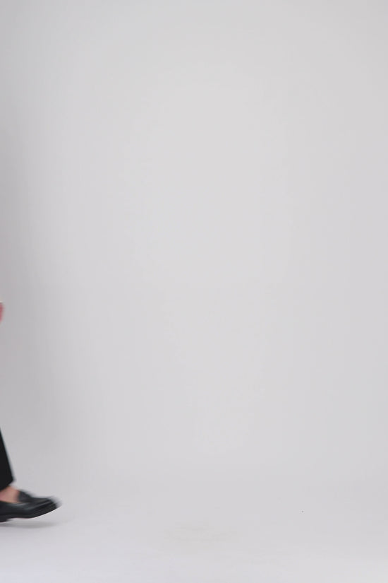 Un jean noir droit, élégant et fonctionnel, avec rivets métalliques et finitions soignées pour un style raffiné.