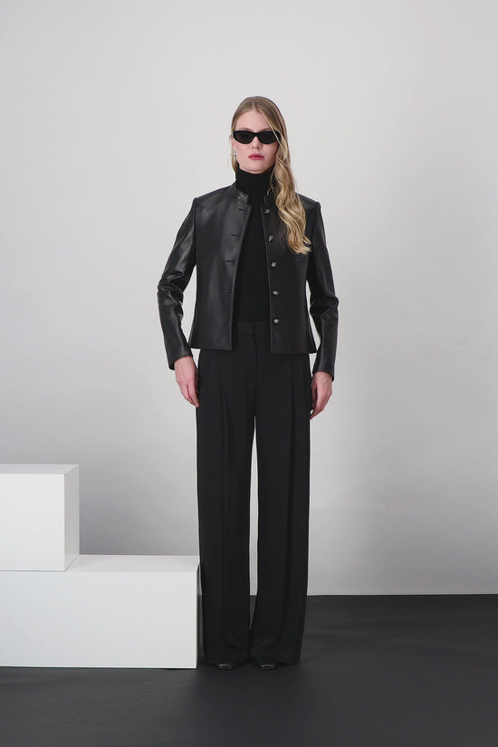 Veste en cuir noire, coupe droite avec manches longues et boutons blasons raffinés.