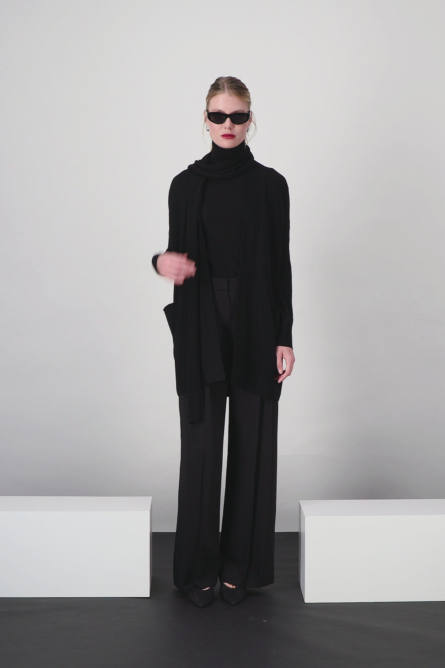Gilet long noir, sans bouton, silhouette enveloppante et fluide.