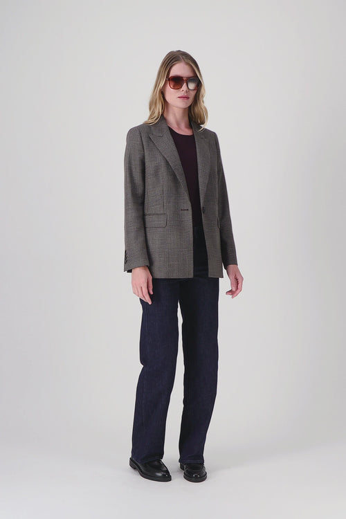 Cette veste courte en laine vierge se distingue par son motif tartan subtil et sa coupe droite