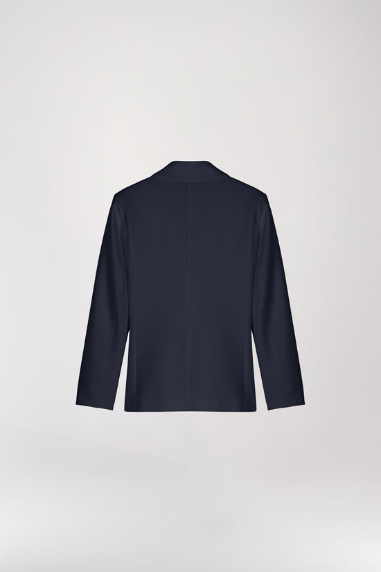 Veste tailleur cintrée marine avec col élégant et boutonnage simple, soulignant la silhouette. Les poches plaquées surdimensionnées ajoutent une touche contemporaine. Le monogramme gravé d'Apostrophe apporte une signature raffinée à ce modèle chic.