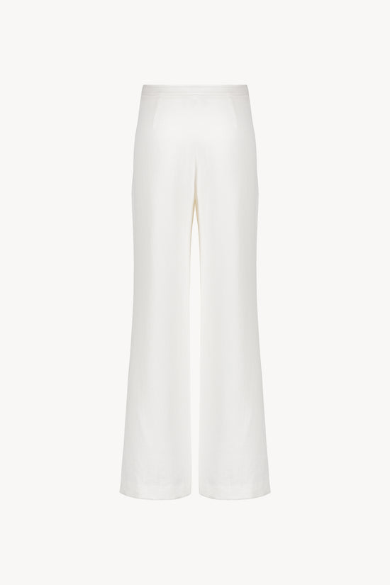 Ce pantalon en lin blanc cassé avec ses poches italiennes et sa coupe droite