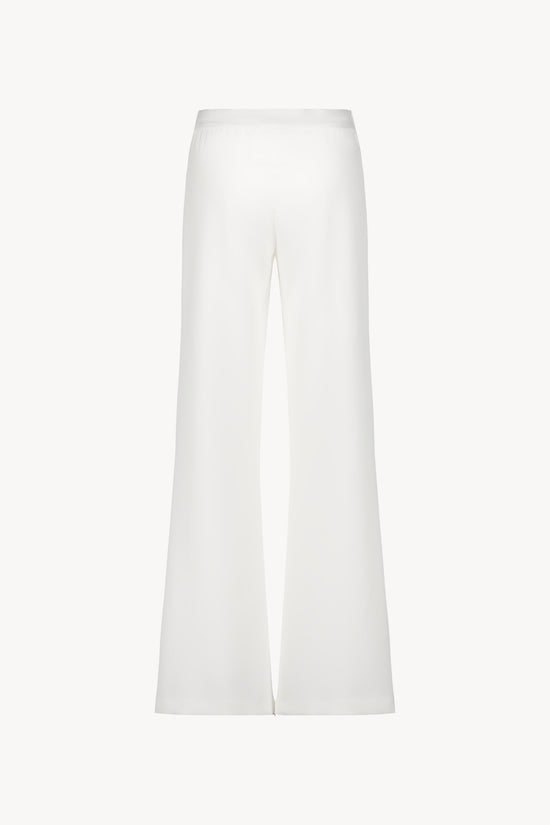 Pantalon évasé blanc casse avec des plis délicats et une coupe fluide.