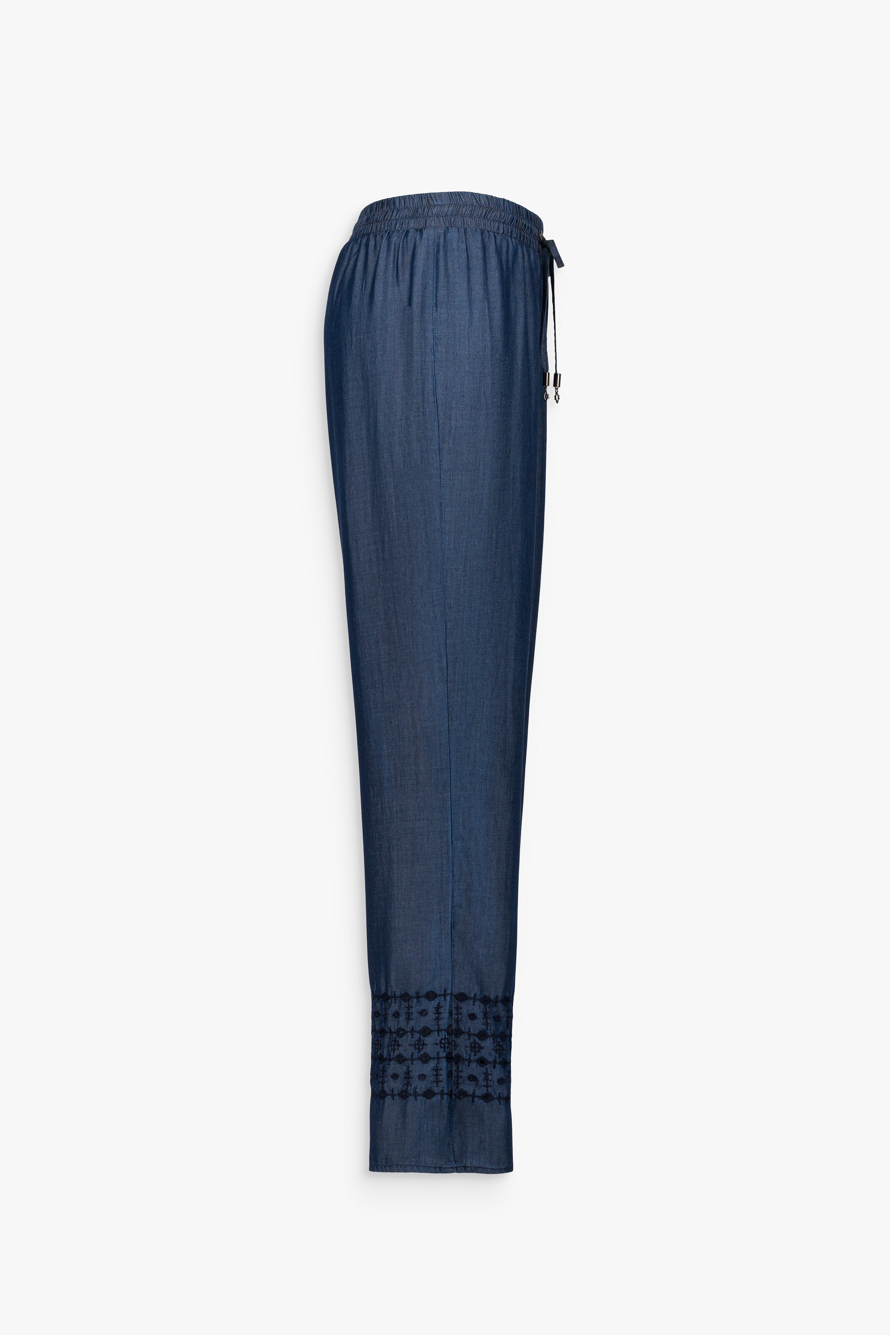 Pantalon fluide en chambray denim, teinté d’un bleu subtilement délavé. Taille élastique et détail brodé 