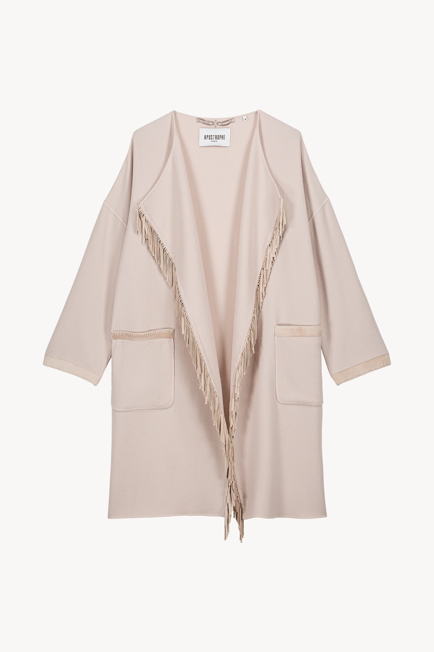 Ce manteau court bi-matière béton combine laine douce et daim, avec un col drapé fluide et des franges décoratives.