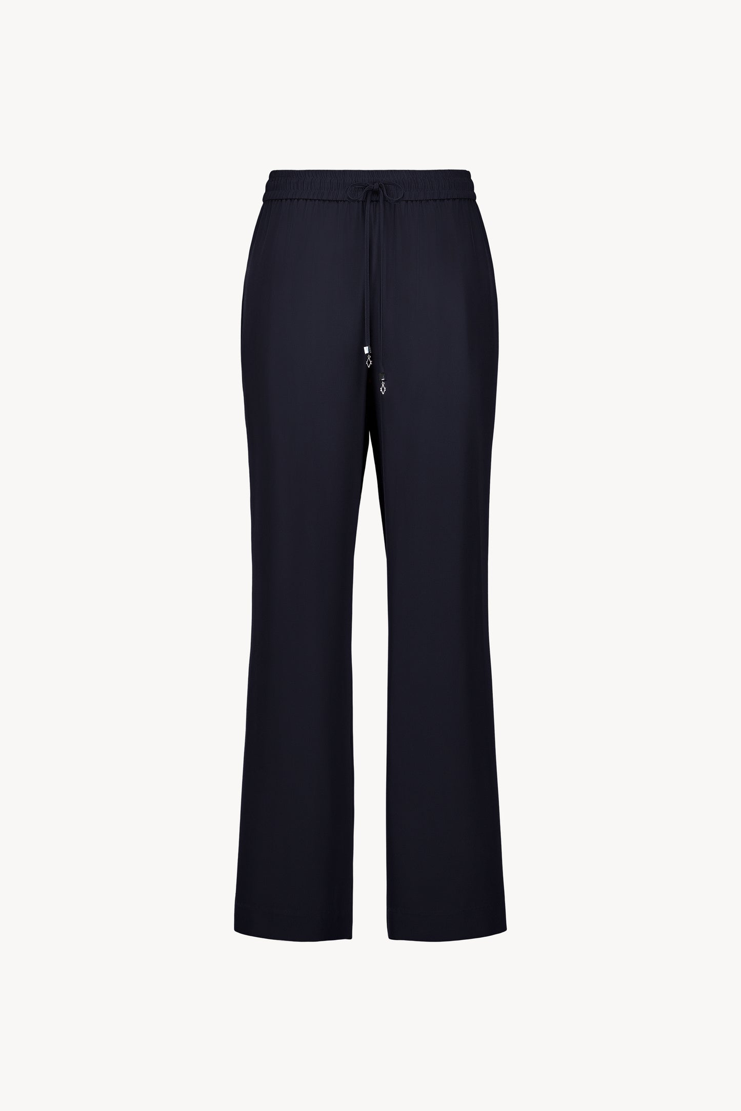 Ce pantalon fluide en soie marine, avec taille élastiquée et cordon ajustable