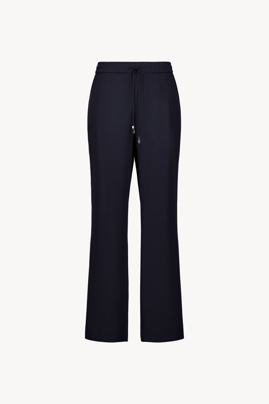 Ce pantalon fluide en soie marine, avec taille élastiquée et cordon ajustable